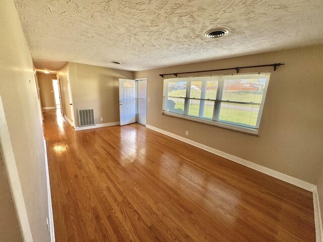 spare room featuring wood-type flooring and a textured ceiling