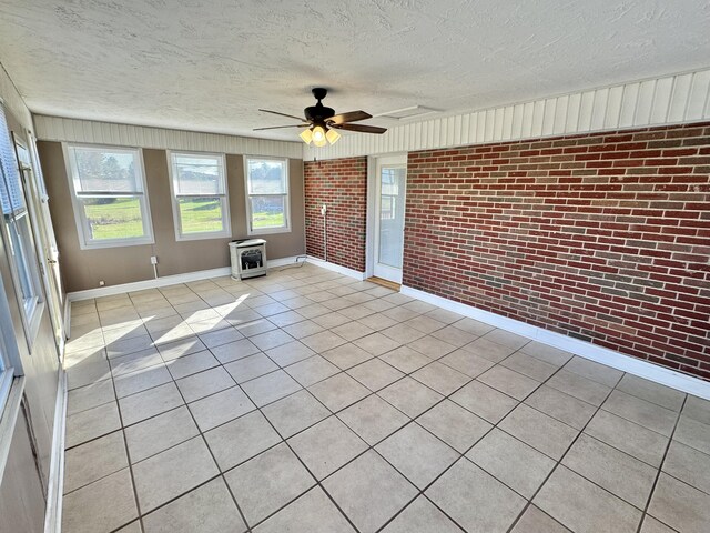 unfurnished sunroom featuring heating unit, a wood stove, and ceiling fan