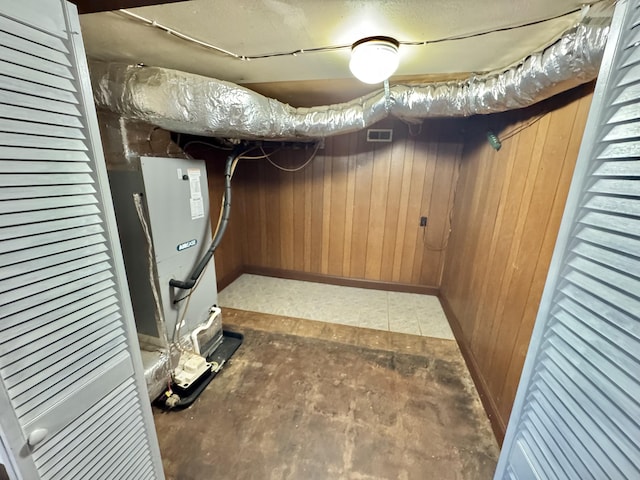 basement featuring heating unit and wooden walls