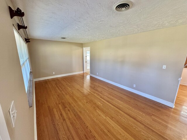 spare room with a textured ceiling and light wood-type flooring