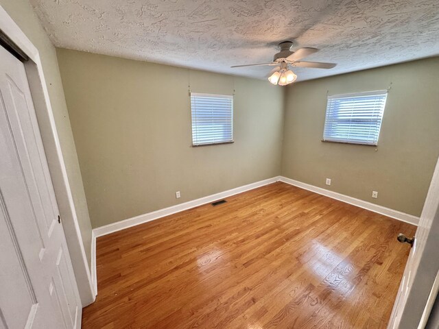 unfurnished bedroom featuring hardwood / wood-style floors, ceiling fan, a textured ceiling, and a closet