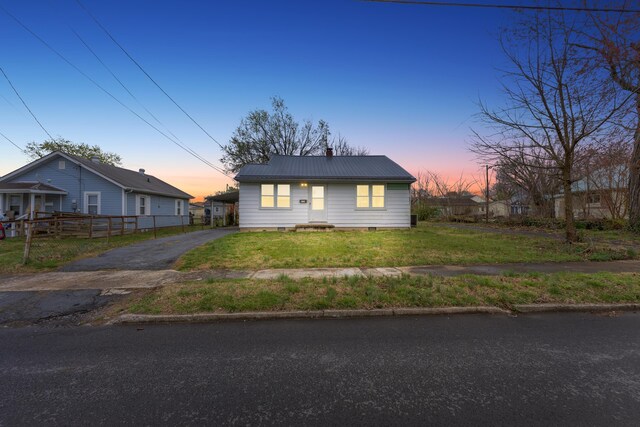 view of front of property with a chimney, fence, aphalt driveway, a front lawn, and metal roof