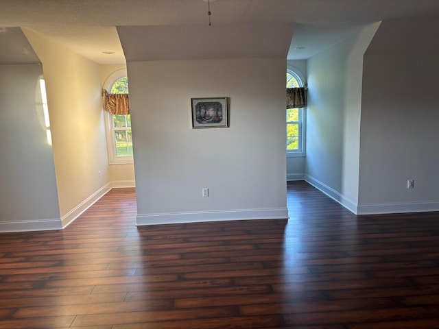 empty room with dark wood finished floors and baseboards