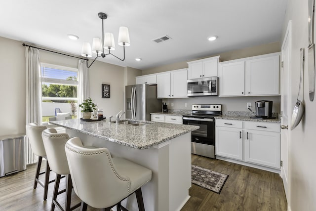 5021 Cottonseed Way, Morristown, TN 37813 - kitchen featuring appliances with stainless steel finishes, white cabinets, a kitchen island with sink, dark wood-style floors, and light stone countertops