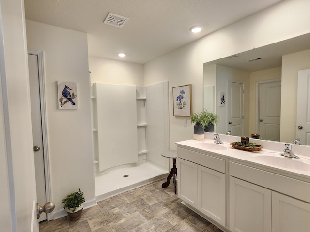 full bath with a sink, a walk in shower, double vanity, and visible vents