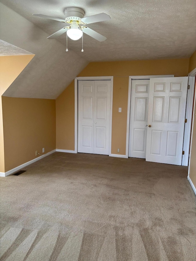 additional living space featuring vaulted ceiling, ceiling fan, light carpet, and a textured ceiling