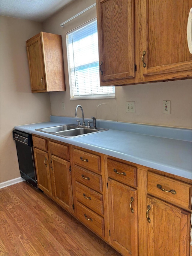 kitchen with black dishwasher, sink, and light wood-type flooring