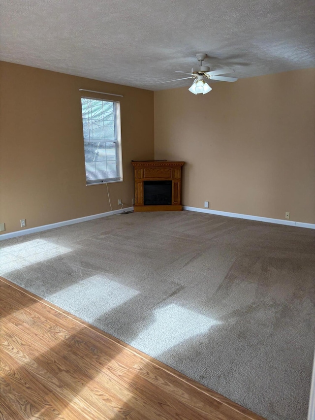 unfurnished living room featuring ceiling fan, carpet floors, and a textured ceiling