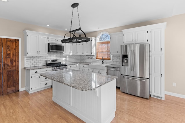 kitchen featuring stainless steel appliances, white cabinetry, and a center island