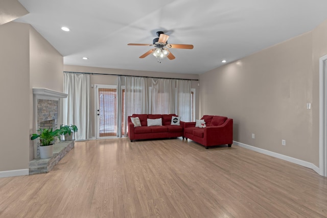 living room featuring a fireplace, light hardwood / wood-style flooring, and ceiling fan