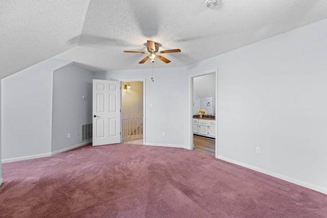 unfurnished bedroom with connected bathroom, ceiling fan, a textured ceiling, and carpet