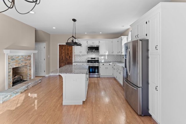 kitchen featuring a kitchen island, light stone countertops, white cabinets, and appliances with stainless steel finishes