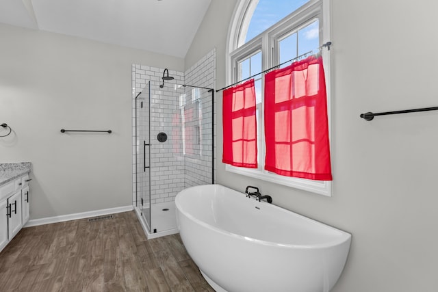 bathroom with vanity, hardwood / wood-style floors, vaulted ceiling, and independent shower and bath