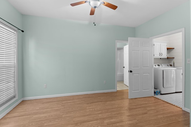 clothes washing area with ceiling fan, cabinets, washing machine and dryer, and light wood-type flooring