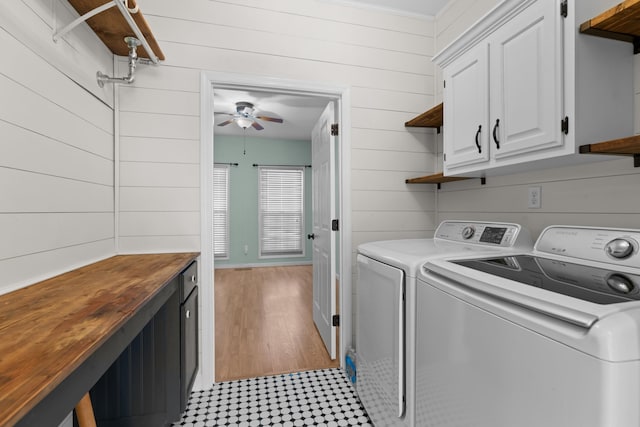 laundry area featuring cabinets, ceiling fan, washer and clothes dryer, and wood walls