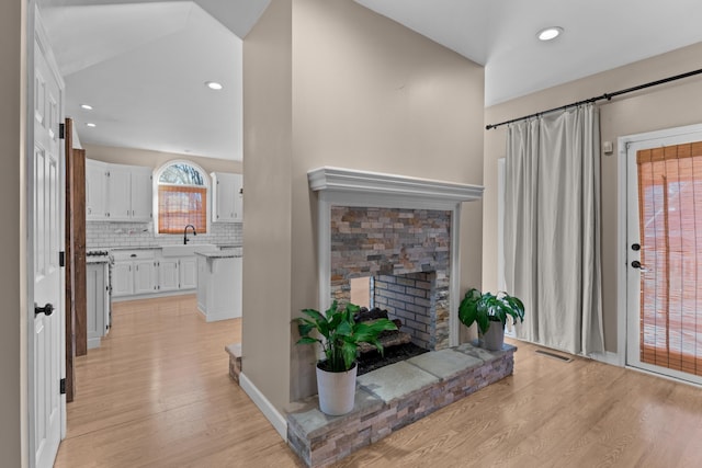 living room featuring sink, a fireplace, and light hardwood / wood-style floors