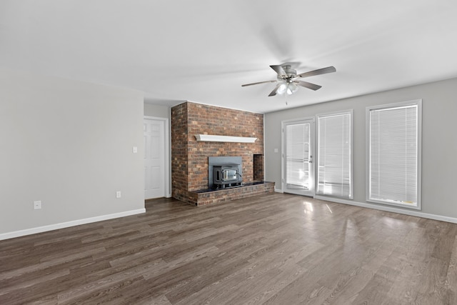 unfurnished living room featuring ceiling fan, a wood stove, and dark hardwood / wood-style flooring