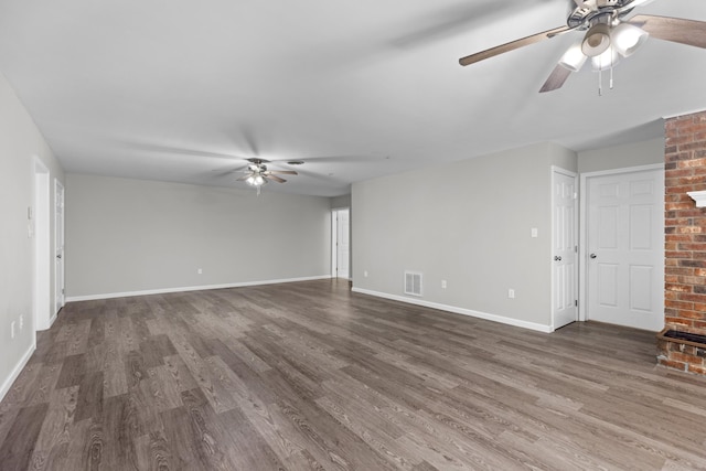 unfurnished living room featuring a brick fireplace, dark wood-type flooring, and ceiling fan