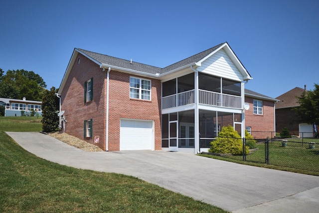 view of front of home featuring a sunroom, a front yard, and a garage