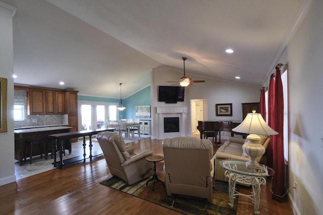 living room featuring lofted ceiling, dark wood-type flooring, ceiling fan, and crown molding