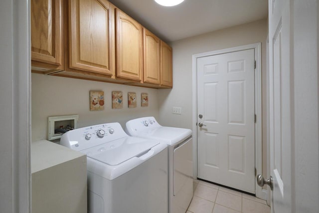 laundry area with washing machine and clothes dryer, light tile patterned floors, and cabinets