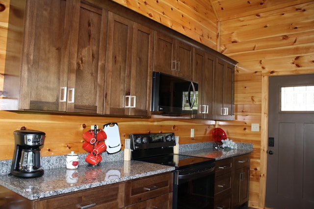 kitchen featuring wood walls, lofted ceiling, black electric range, dark stone countertops, and dark brown cabinetry