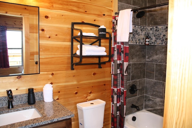 full bathroom with wooden walls, vanity, shower / tub combo, and toilet