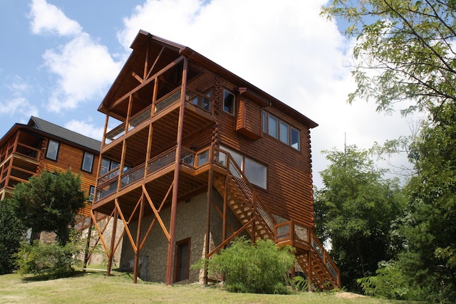 rear view of property featuring a balcony and a yard