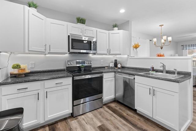 kitchen featuring sink, hanging light fixtures, a notable chandelier, white cabinetry, and stainless steel appliances