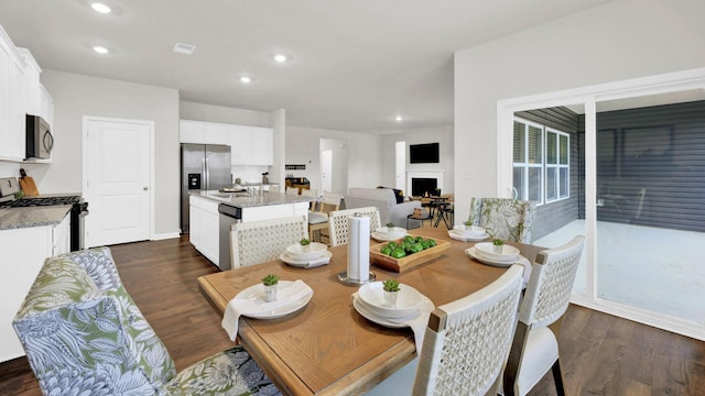 dining room featuring a fireplace, dark wood-style floors, and recessed lighting