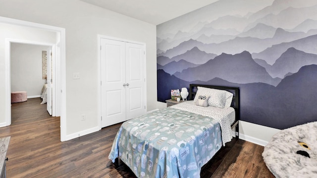 bedroom with wood finished floors, a closet, and baseboards