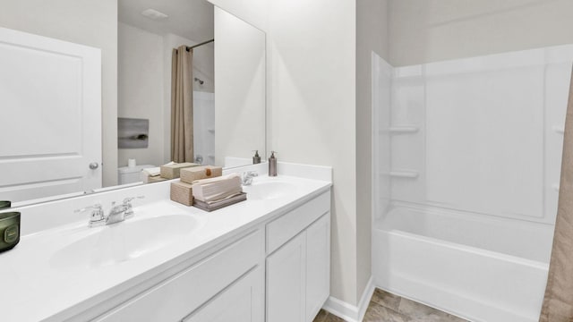 bathroom with toilet, double vanity, and baseboards