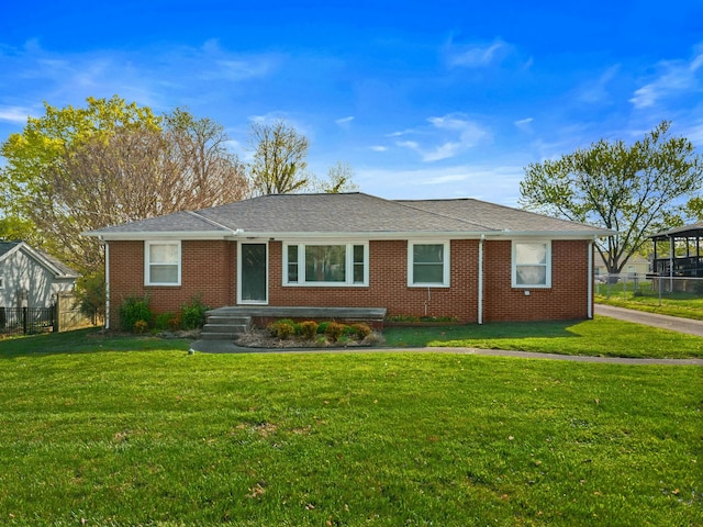 ranch-style home featuring fence, a front lawn, and brick siding