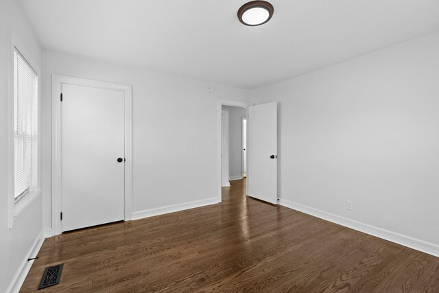 spare room with dark wood-type flooring, baseboards, and visible vents