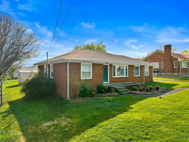 back of property featuring brick siding, fence, and a lawn