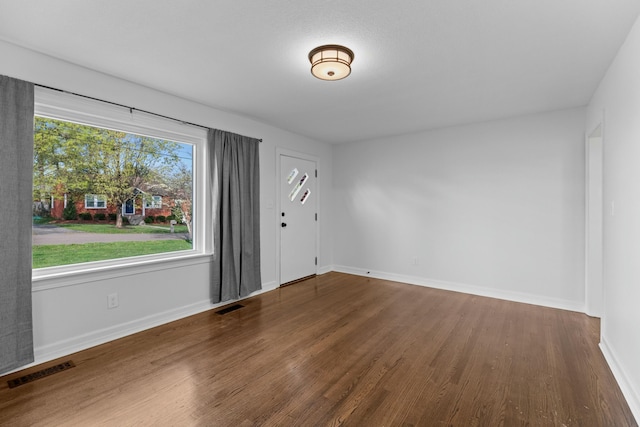 empty room featuring wood finished floors, baseboards, and visible vents