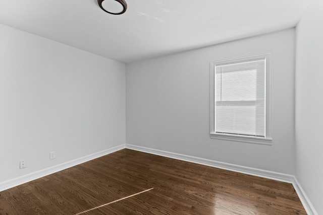 empty room with dark wood-style flooring and baseboards