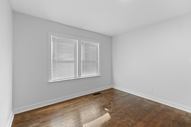unfurnished room featuring wood finished floors, baseboards, and visible vents