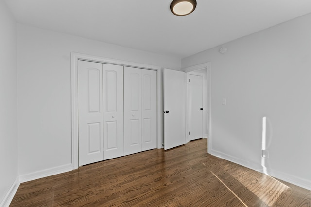 unfurnished bedroom with a closet, baseboards, and wood finished floors