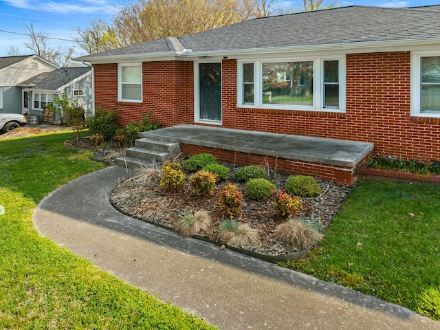 view of front of home featuring a front yard, brick siding, and a shingled roof