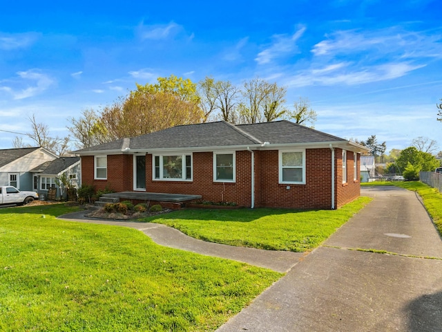 ranch-style house with brick siding, a front lawn, and roof with shingles