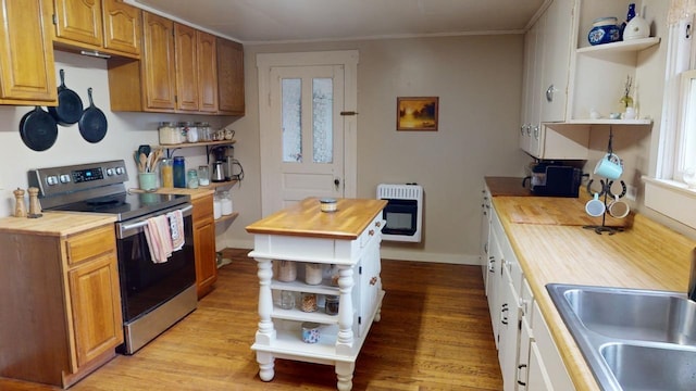 kitchen with heating unit, sink, butcher block counters, light hardwood / wood-style floors, and stainless steel range with electric cooktop