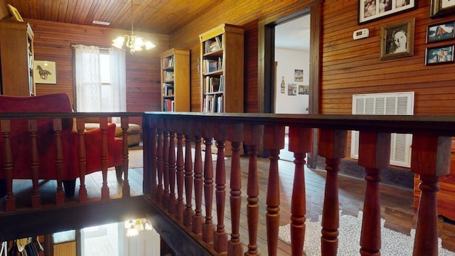 hall featuring a notable chandelier, wood ceiling, and wooden walls