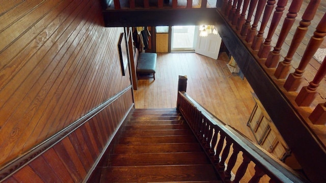 stairs featuring hardwood / wood-style floors and wooden walls