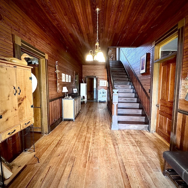 entrance foyer with a chandelier, wood-type flooring, wooden walls, and wooden ceiling