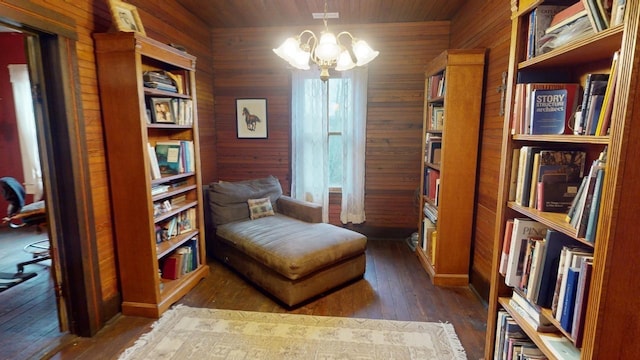 sitting room featuring wood walls, dark hardwood / wood-style flooring, wooden ceiling, and an inviting chandelier