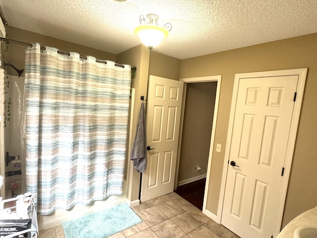 bathroom with tile patterned floors, shower / tub combo with curtain, and a textured ceiling