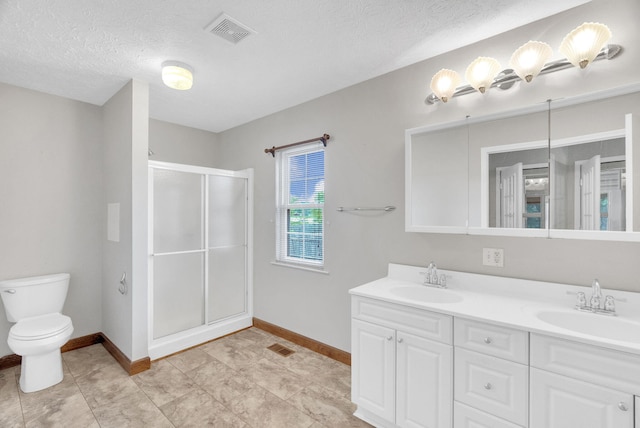 bathroom featuring vanity, toilet, an enclosed shower, and a textured ceiling