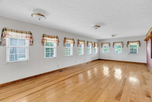 empty room featuring a textured ceiling and light hardwood / wood-style floors