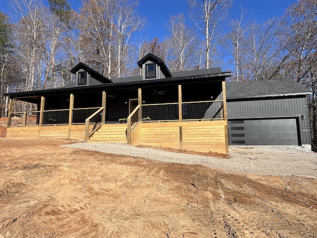 view of front of house with a garage, roof with shingles, and dirt driveway